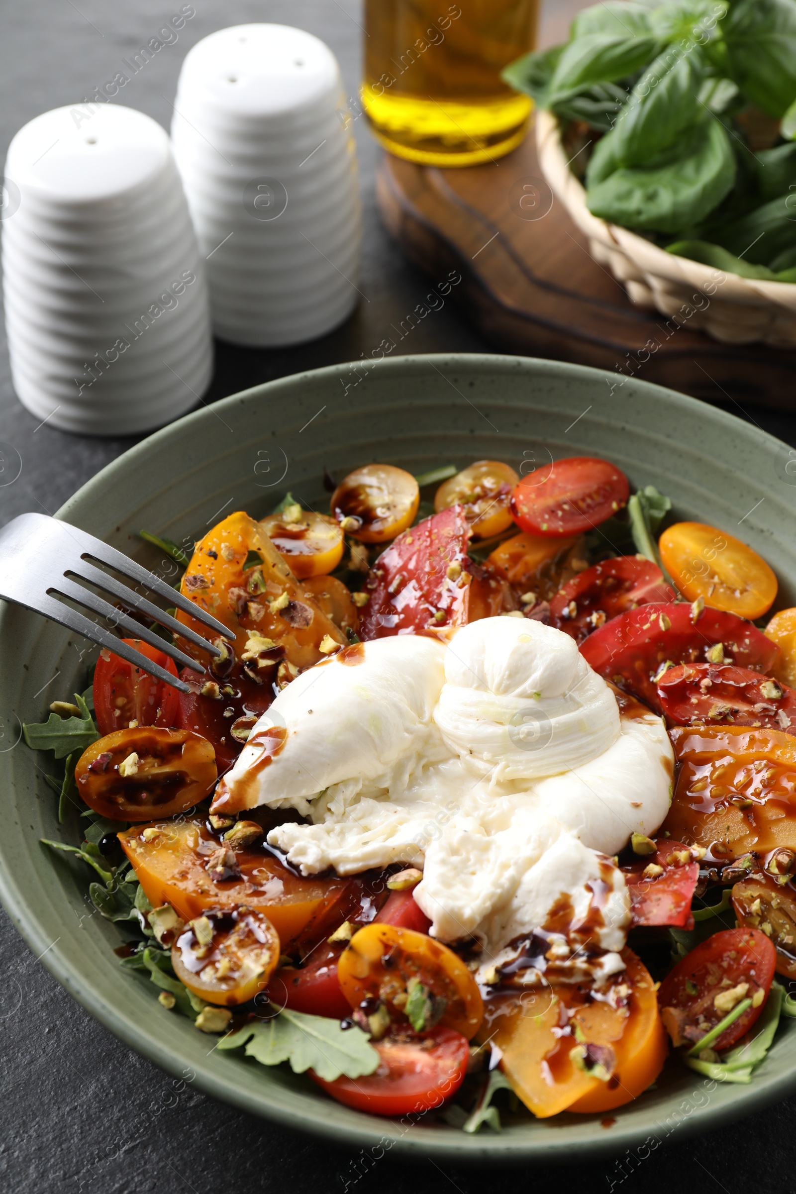 Photo of Fresh delicious burrata salad served on black table, closeup