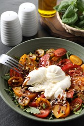 Photo of Fresh delicious burrata salad served on black table, closeup