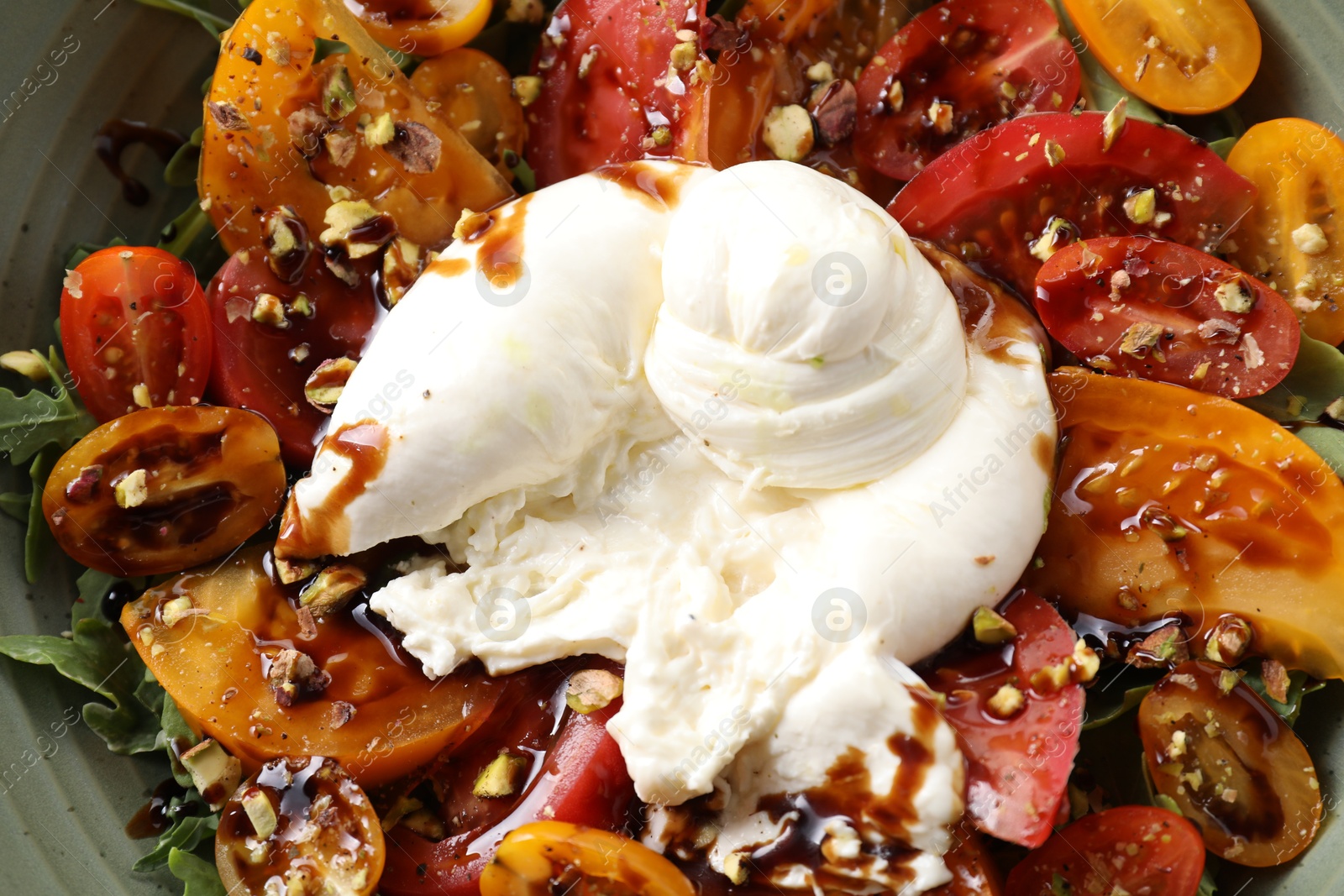 Photo of Fresh delicious burrata salad in bowl, top view