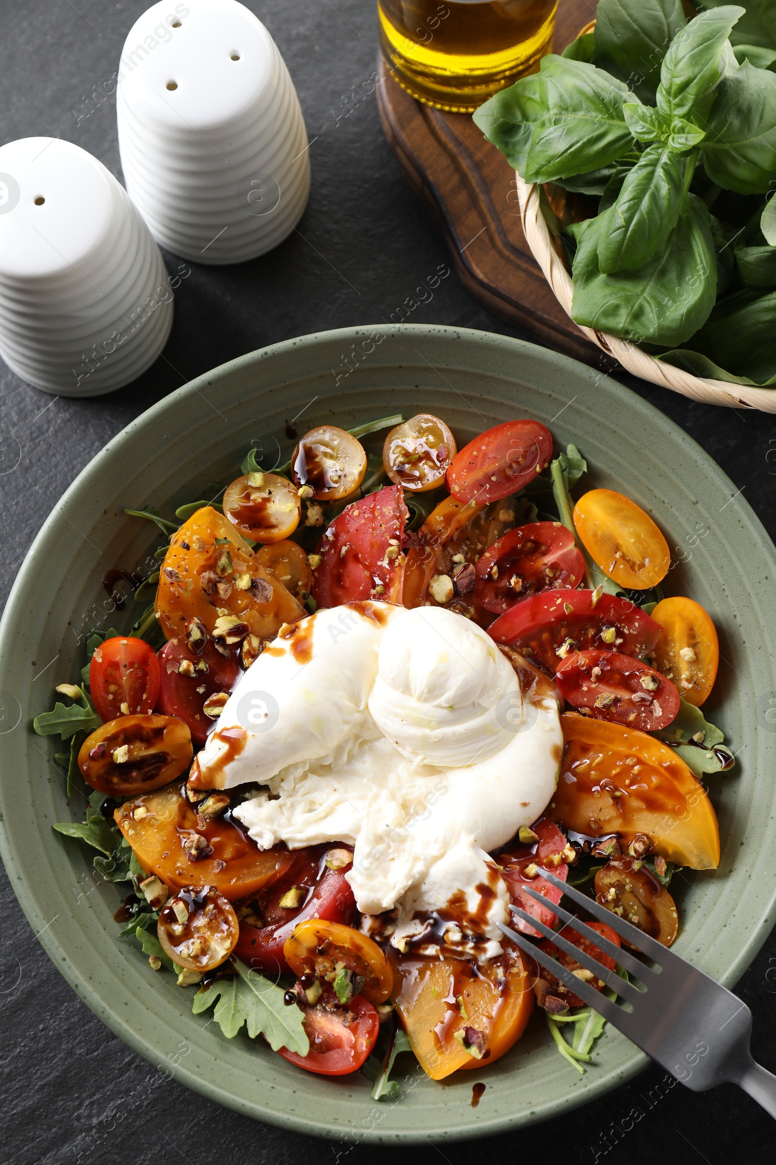 Photo of Fresh delicious burrata salad served on black table, top view