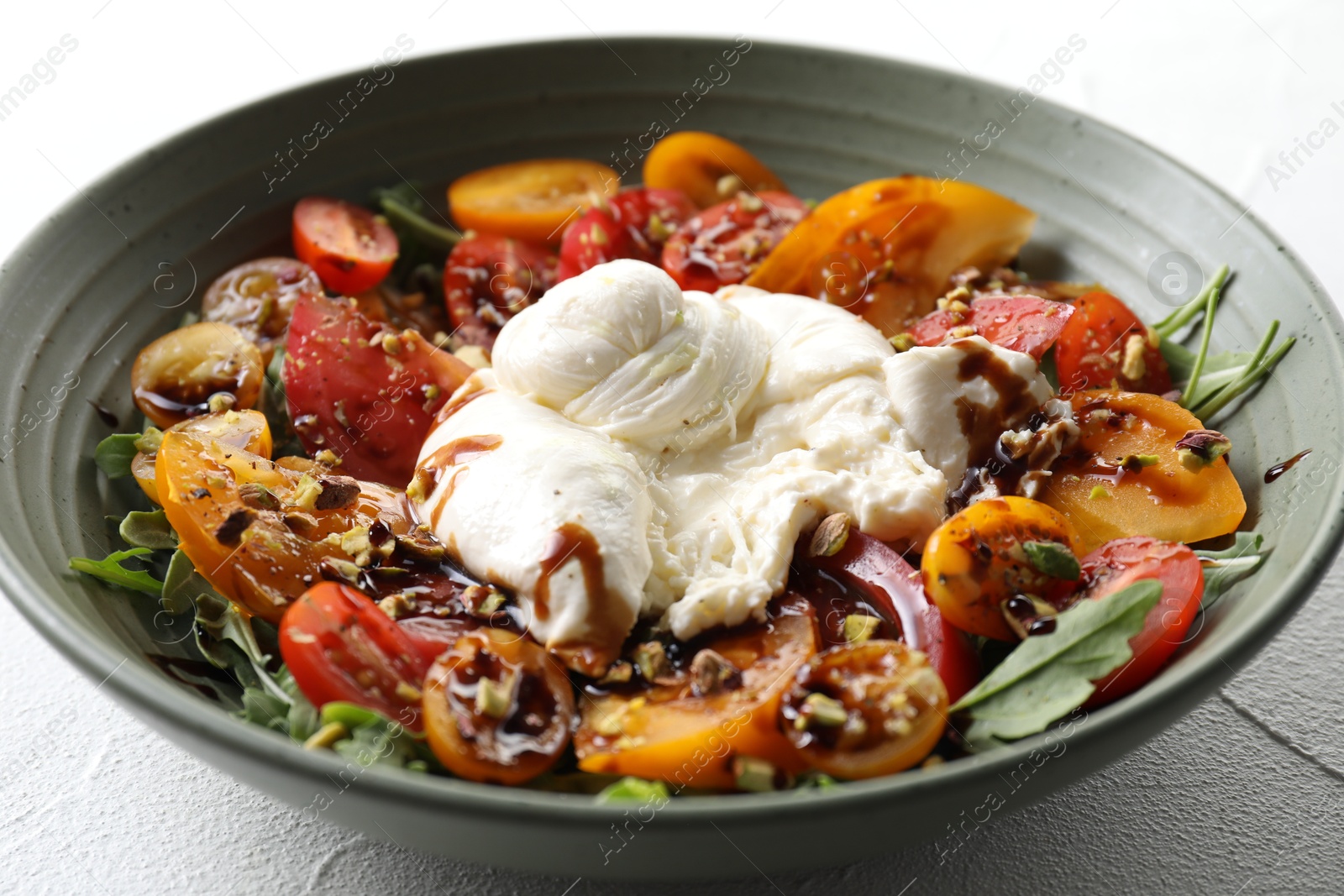 Photo of Fresh delicious burrata salad on white table, closeup