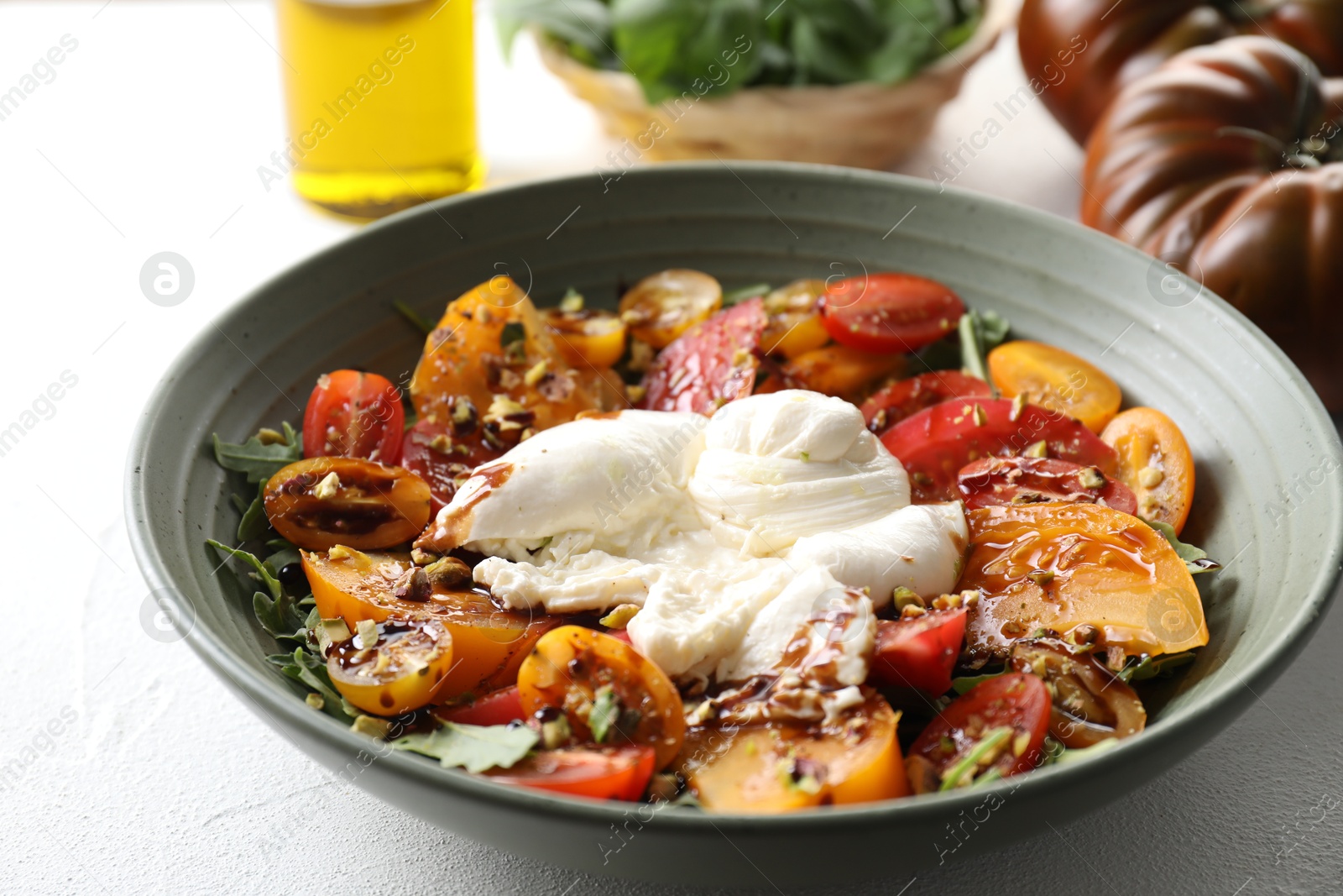 Photo of Fresh delicious burrata salad served on white table, closeup