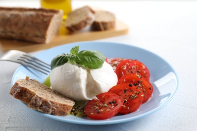 Photo of Delicious burrata cheese, tomatoes, basil and bread on white table, closeup