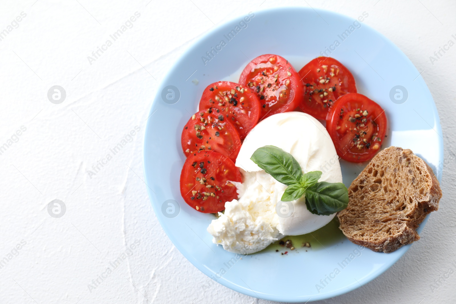 Photo of Delicious burrata cheese, tomatoes, parsley and bread on white table, top view. Space for text