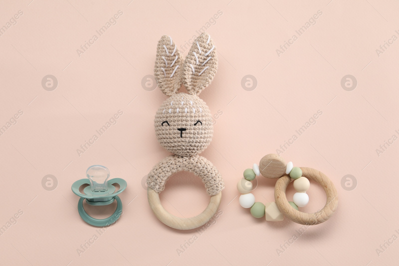 Photo of Wooden rattles and pacifier on beige background, flat lay. Baby accessories