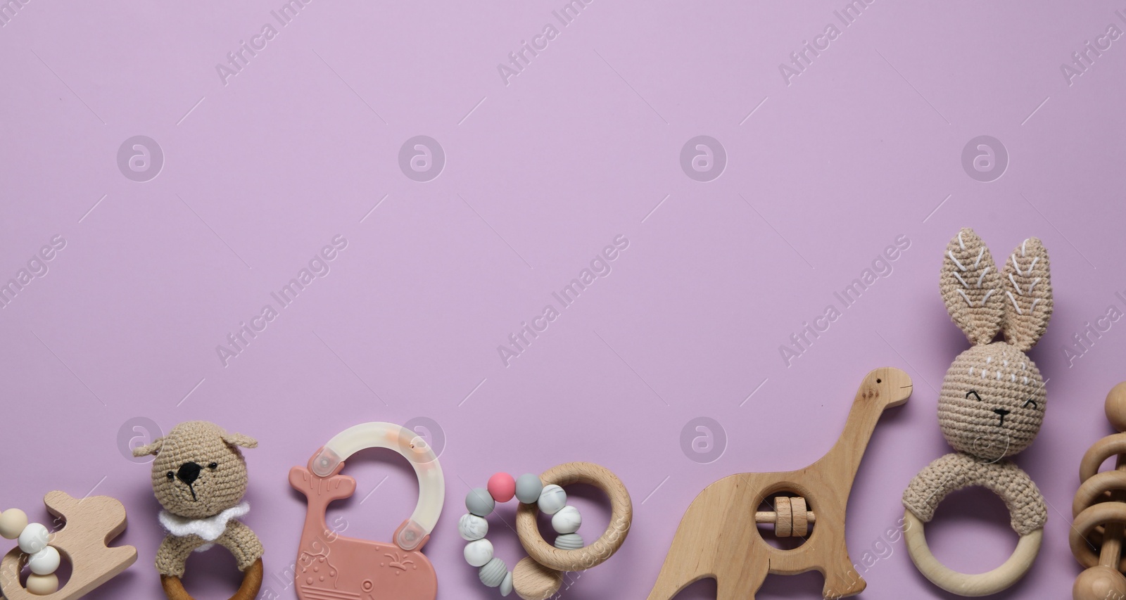 Photo of Colorful rattles on violet background, flat lay with space for text. Baby accessories