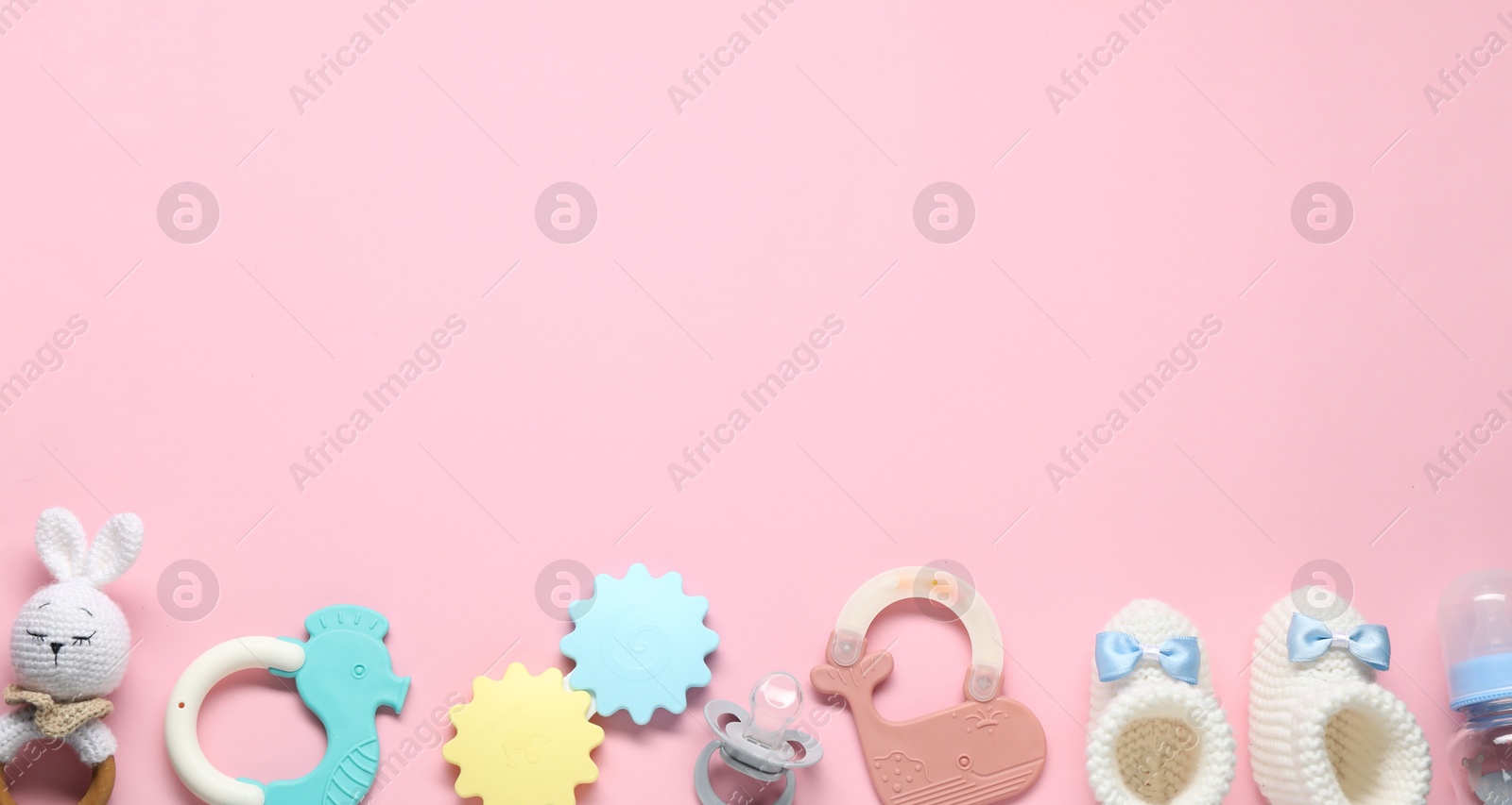 Photo of Colorful rattles and pacifier on pale pink background, flat lay with space for text. Baby accessories