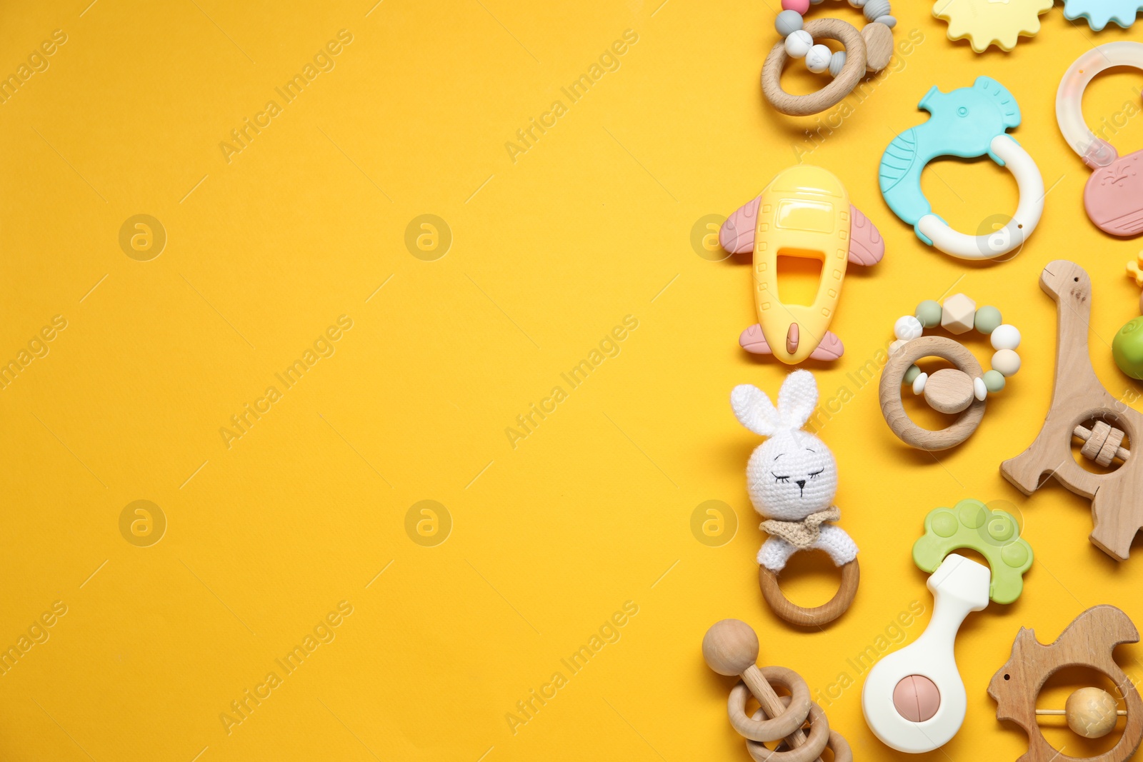 Photo of Colorful rattles on yellow background, flat lay with space for text. Baby accessories