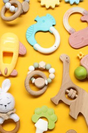 Photo of Colorful rattles on yellow background, flat lay. Baby accessories