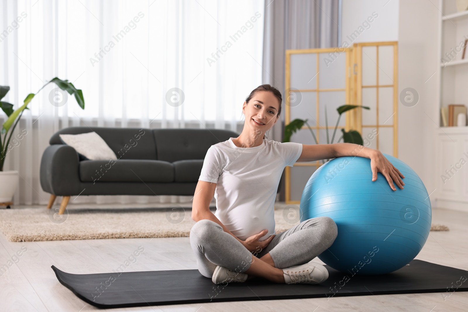 Photo of Beautiful pregnant woman with fitball on exercise mat at home