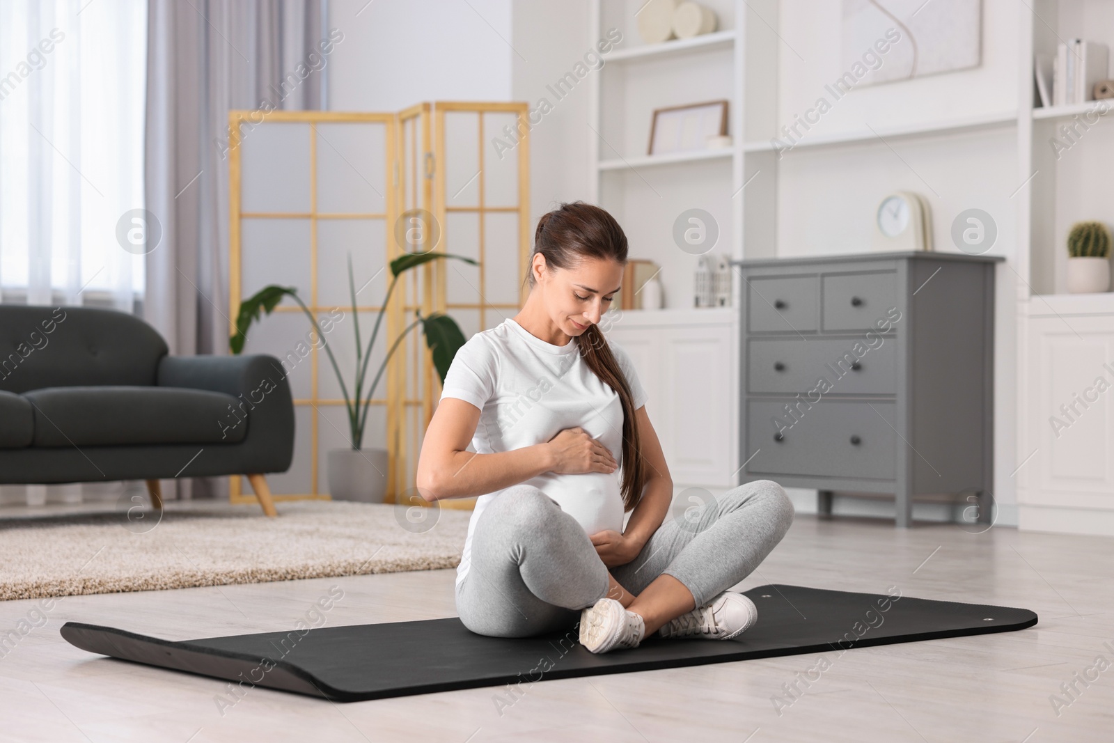 Photo of Beautiful pregnant woman on exercise mat at home