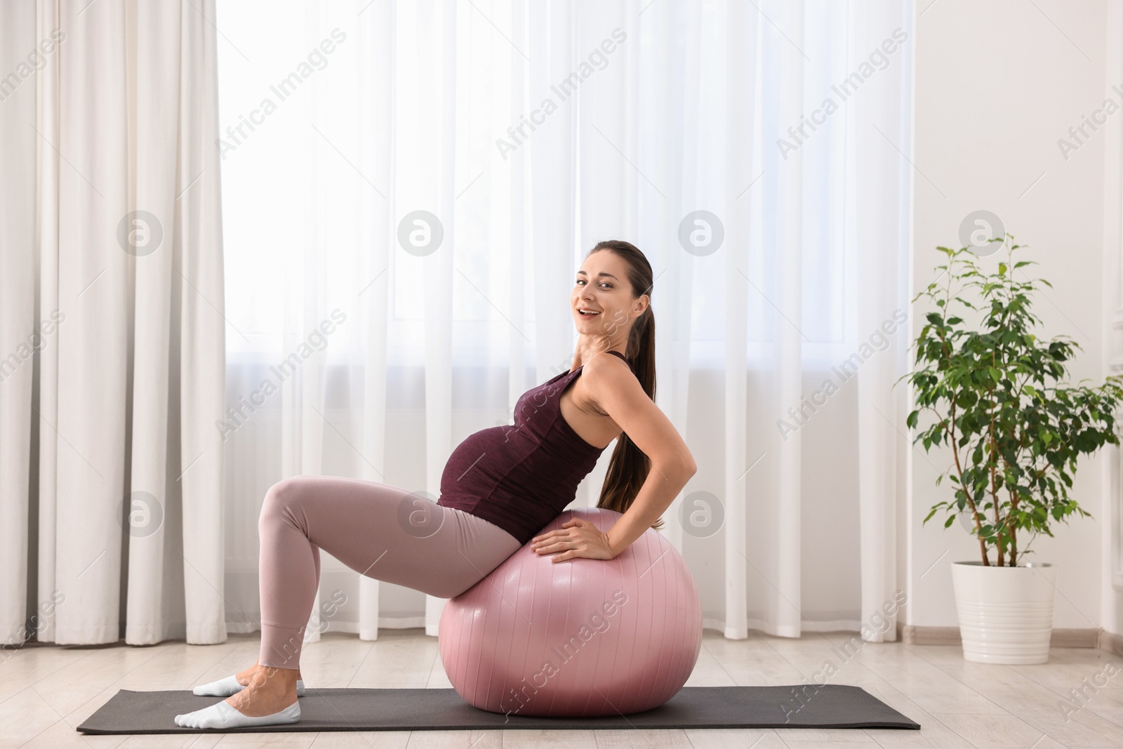 Photo of Beautiful pregnant woman doing exercises on fitball at home