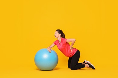 Photo of Beautiful pregnant woman doing exercises with fitball on yellow background