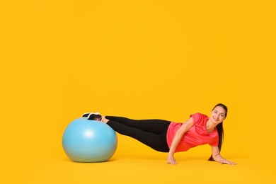 Photo of Beautiful pregnant woman doing exercises with fitball on yellow background