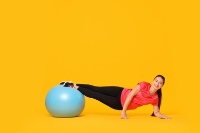 Beautiful pregnant woman doing exercises with fitball on yellow background