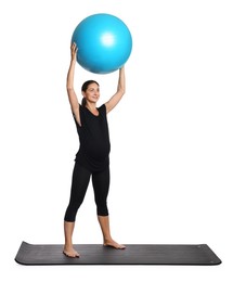 Beautiful pregnant woman with fitball doing exercises on mat against white background