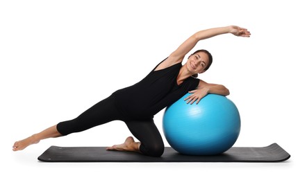 Photo of Beautiful pregnant woman with fitball doing exercises on mat against white background