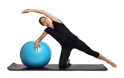 Photo of Beautiful pregnant woman with fitball doing exercises on mat against white background