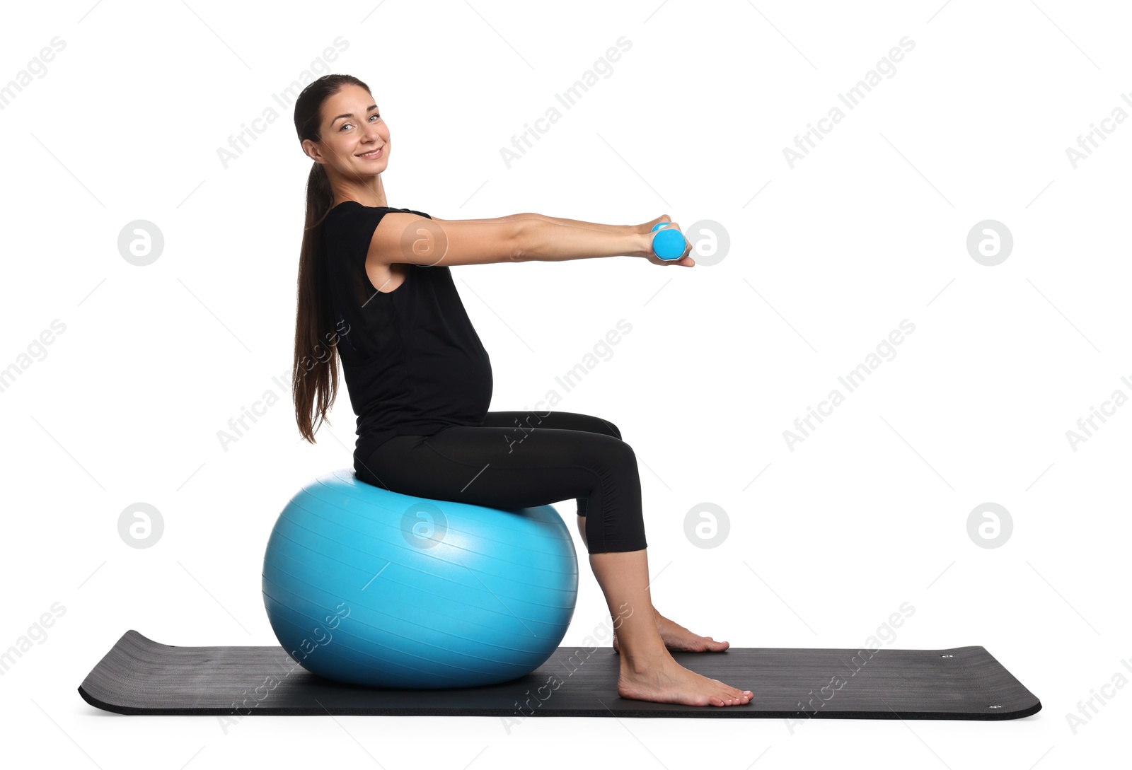 Photo of Beautiful pregnant woman with dumbbells doing exercises on fitball against white background