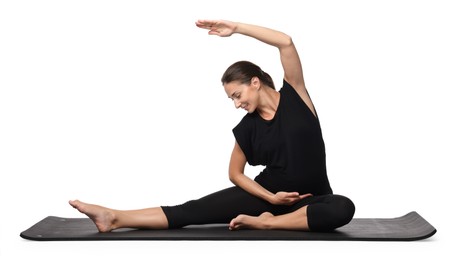 Beautiful pregnant woman doing stretching exercises on mat against white background