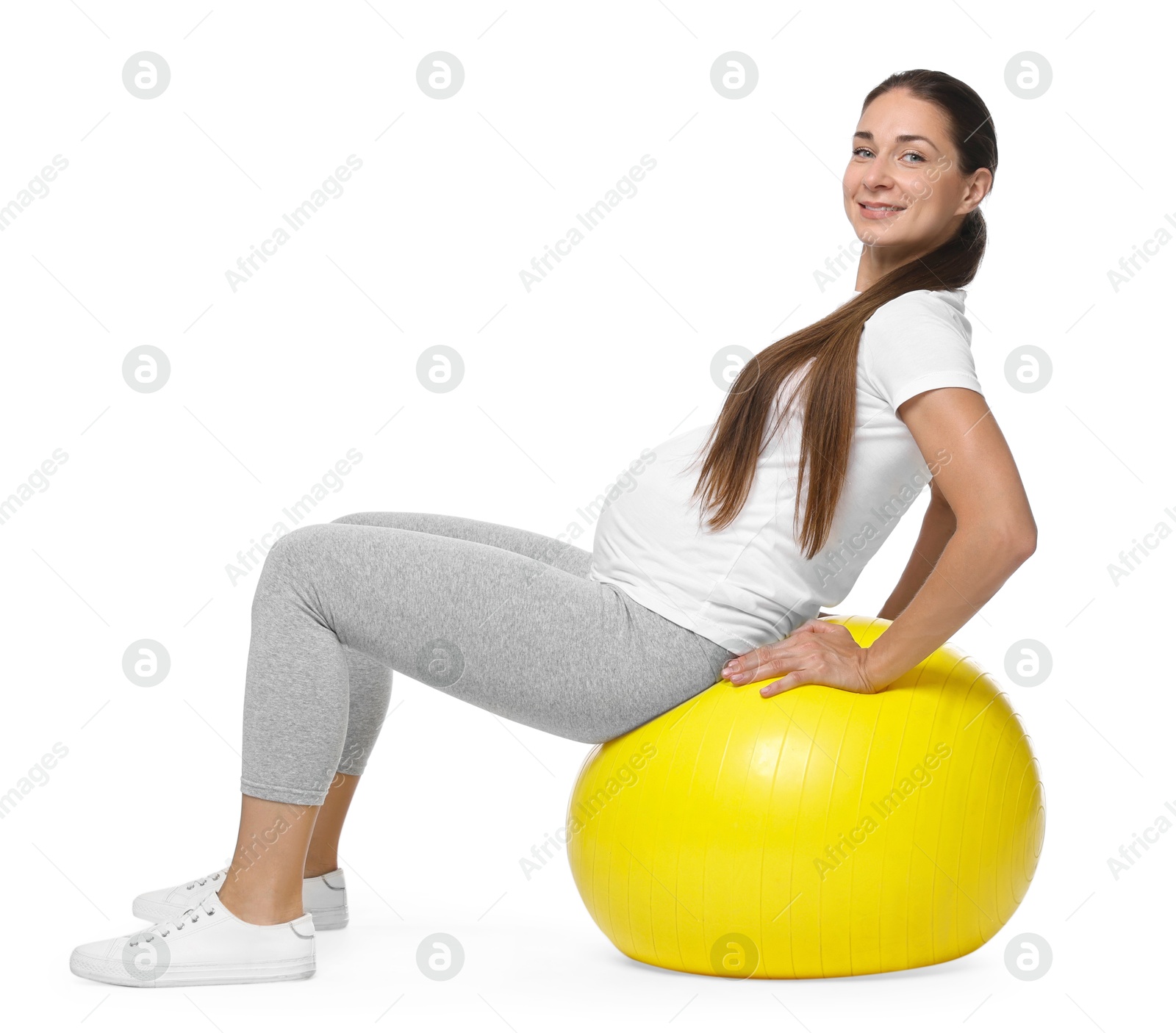 Photo of Beautiful pregnant woman doing exercises on fitball against white background