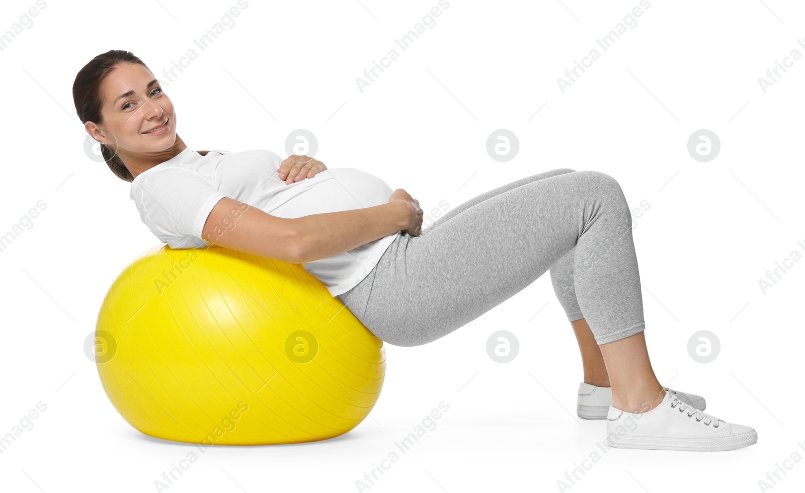 Photo of Beautiful pregnant woman doing exercises on fitball against white background