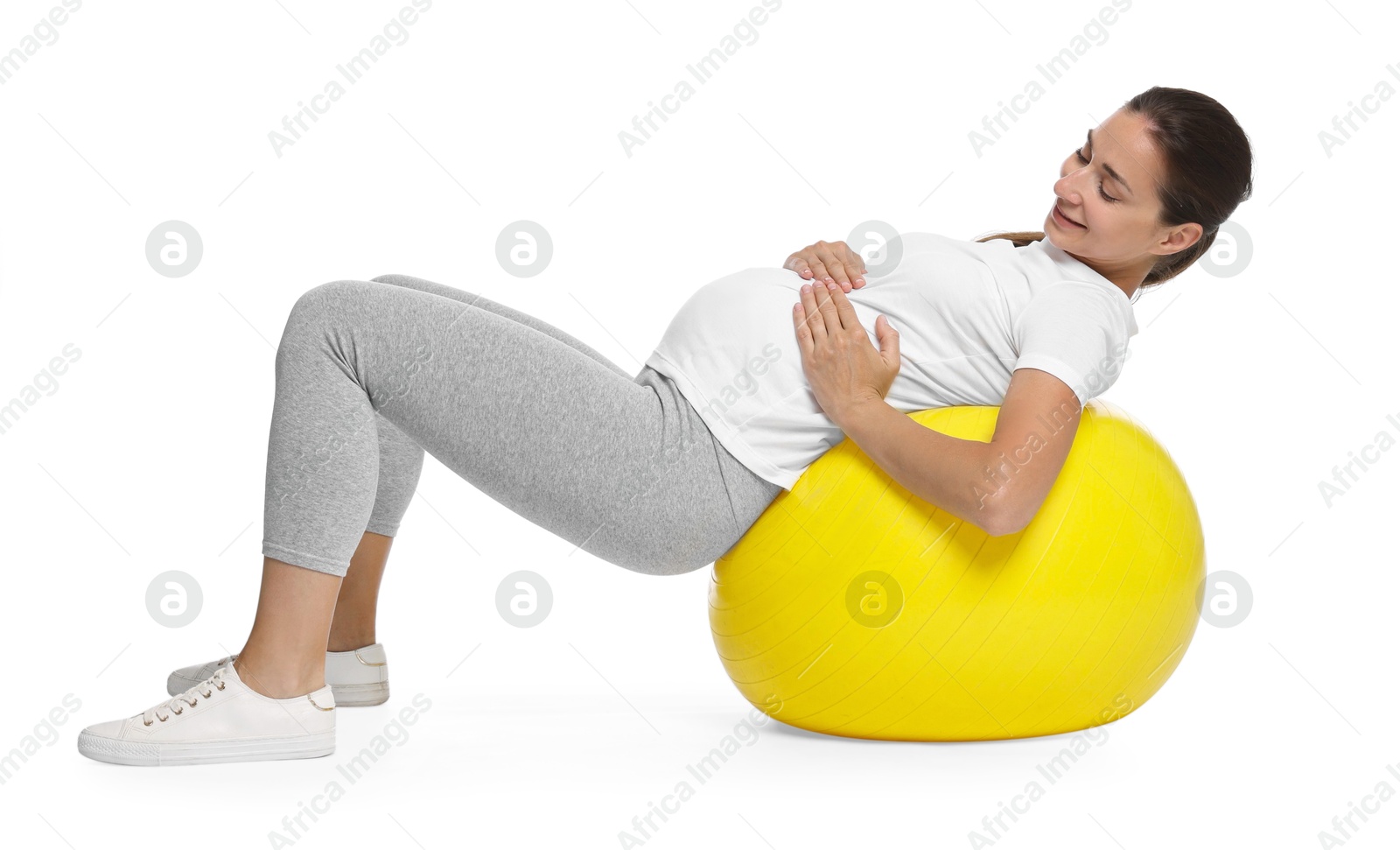 Photo of Beautiful pregnant woman doing exercises on fitball against white background