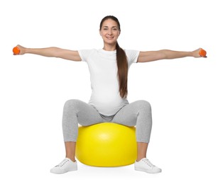 Beautiful pregnant woman with dumbbells doing exercises on fitball against white background