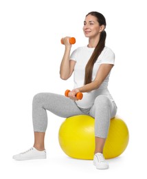 Photo of Beautiful pregnant woman with dumbbells doing exercises on fitball against white background