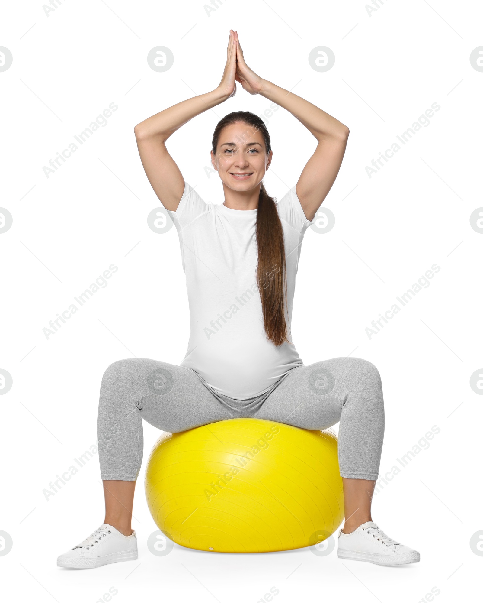 Photo of Beautiful pregnant woman doing exercises on fitball against white background