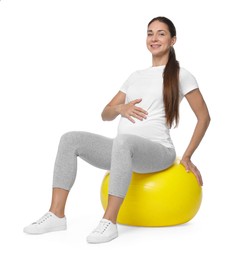 Beautiful pregnant woman doing exercises on fitball against white background