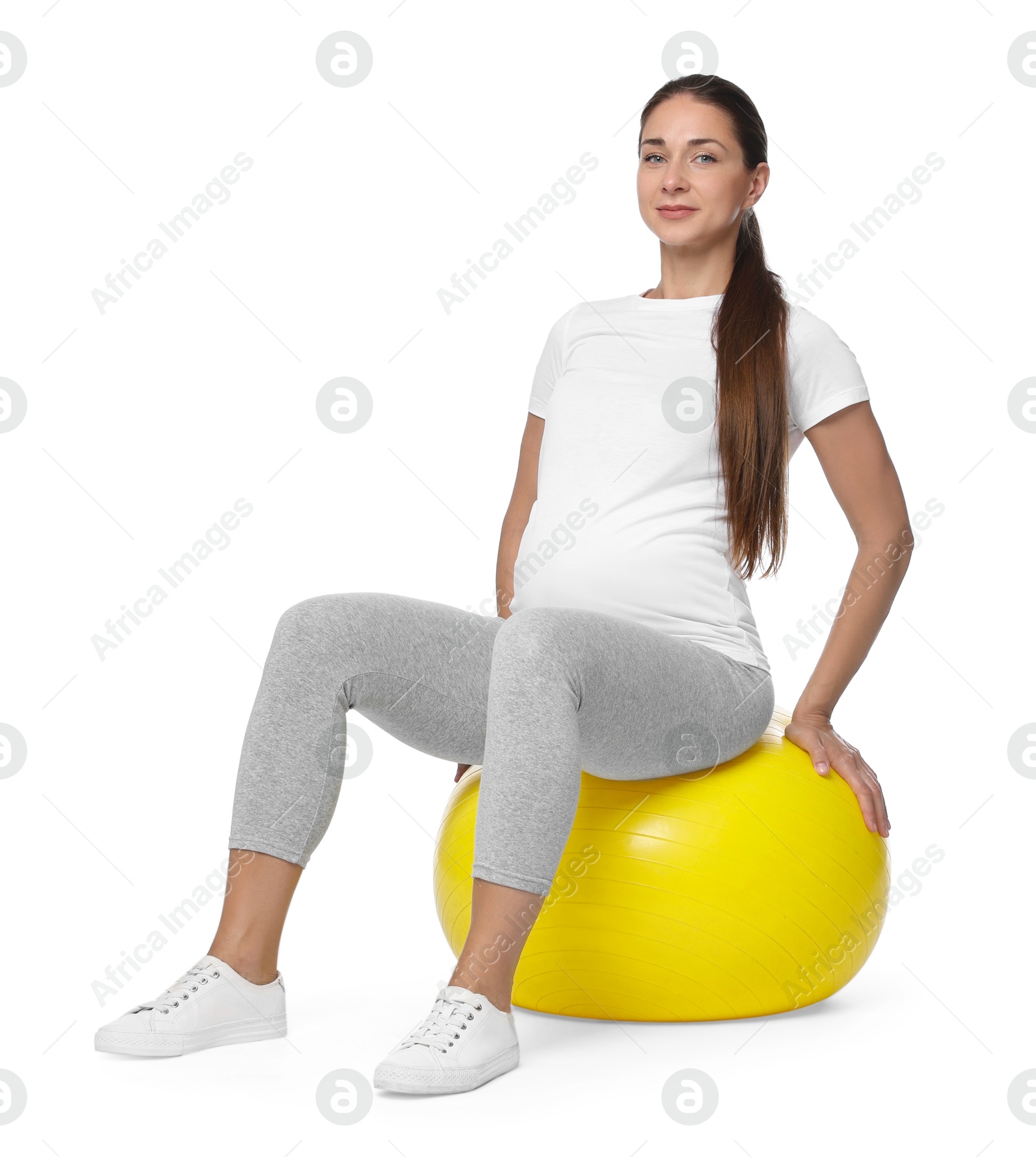 Photo of Beautiful pregnant woman doing exercises on fitball against white background