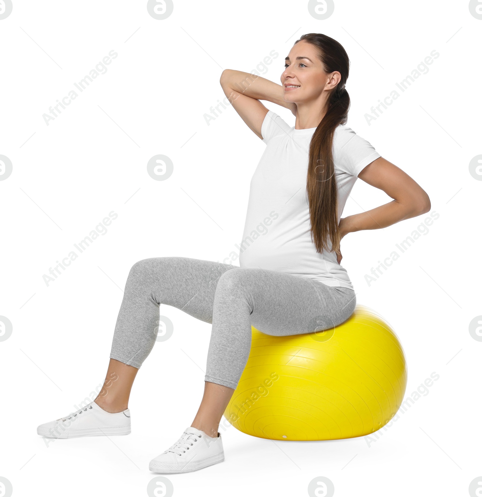 Photo of Beautiful pregnant woman doing exercises on fitball against white background