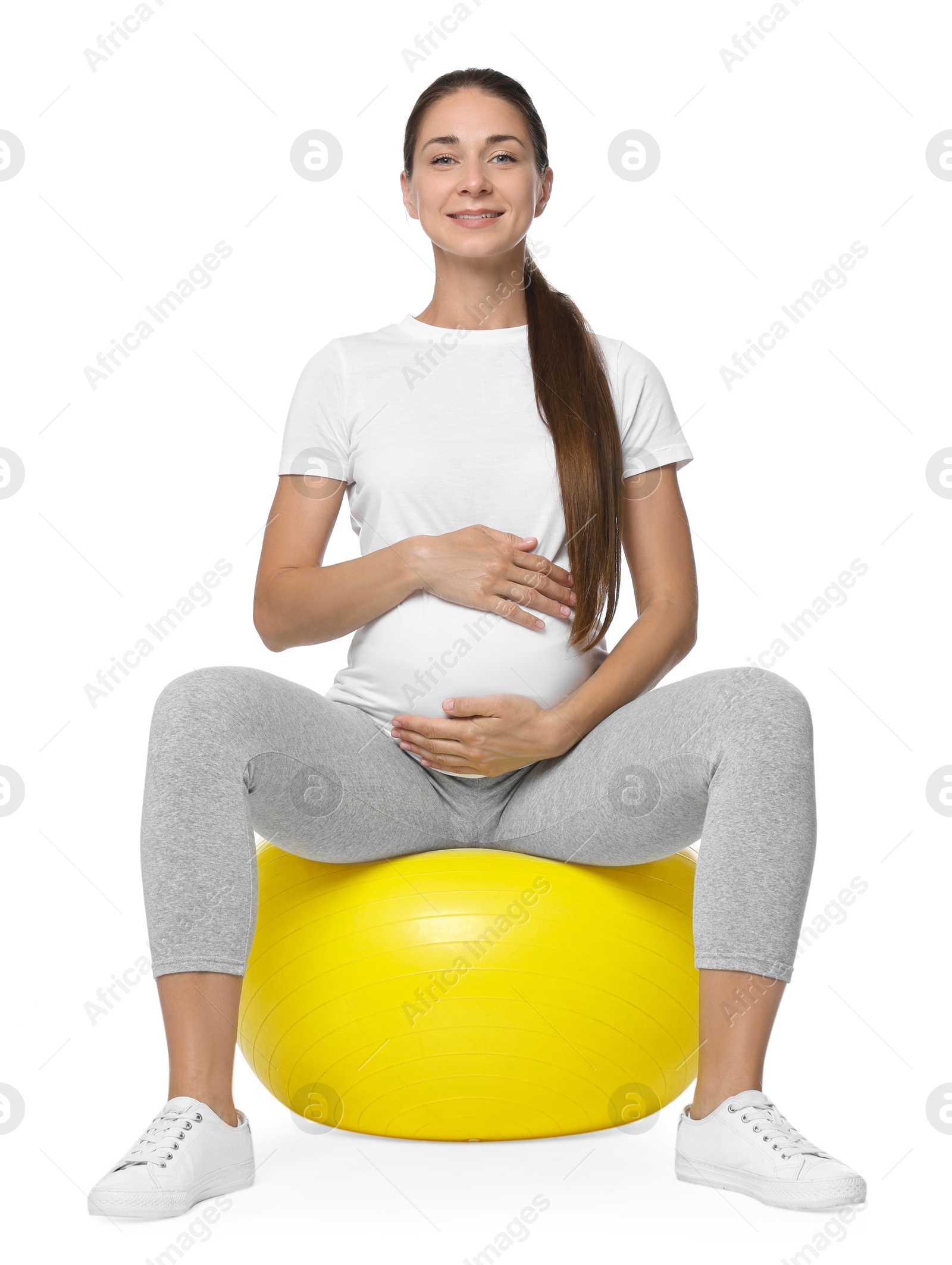 Photo of Beautiful pregnant woman doing exercises on fitball against white background