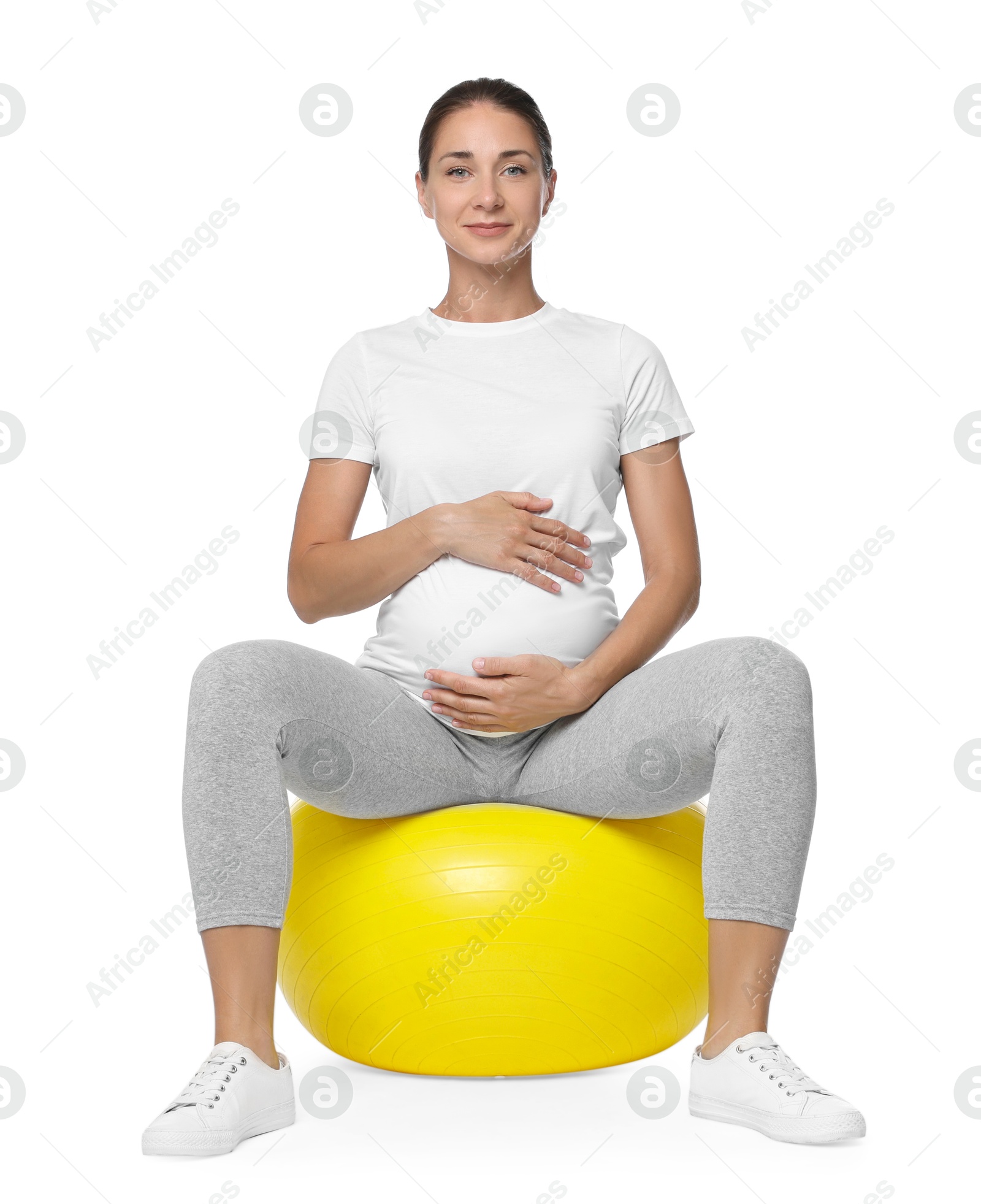 Photo of Beautiful pregnant woman doing exercises on fitball against white background