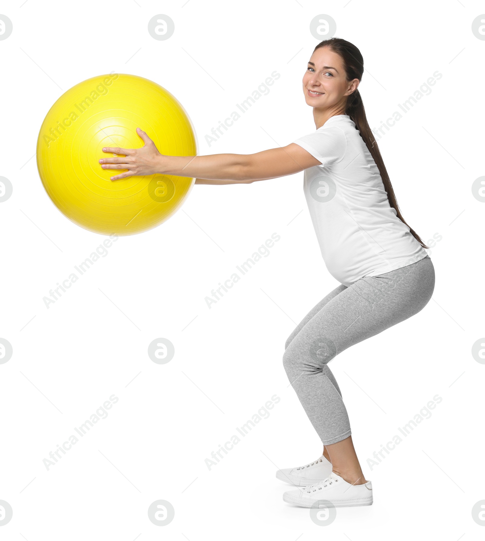 Photo of Beautiful pregnant woman with fitball doing exercises on white background