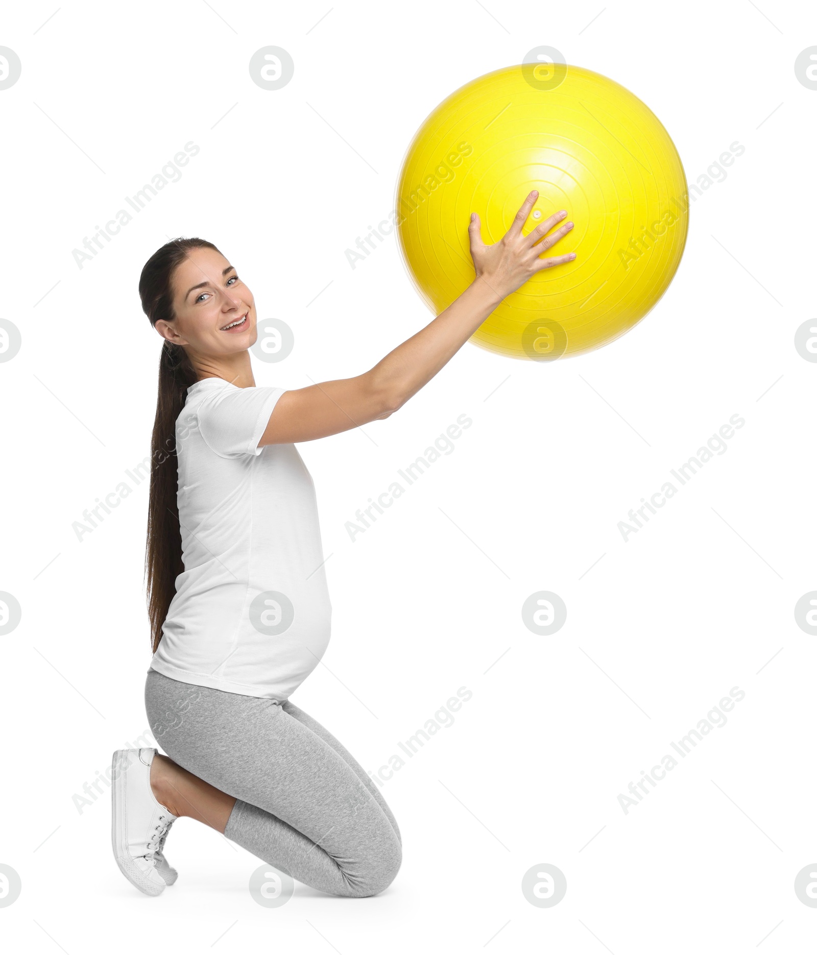 Photo of Beautiful pregnant woman with fitball doing exercises on white background