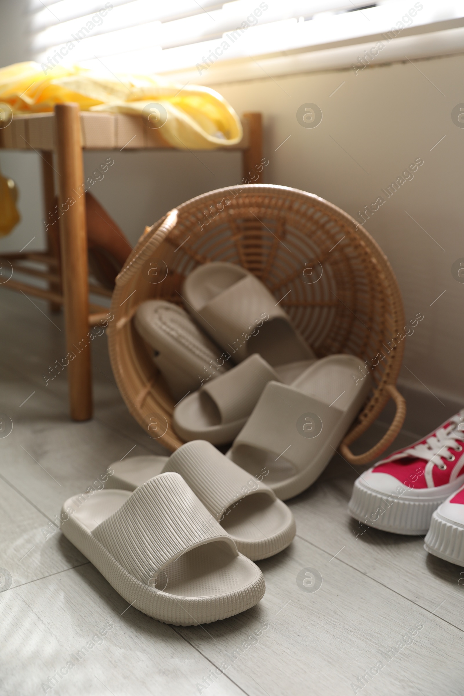 Photo of Basket with slippers for guests and sneakers in entryway at home