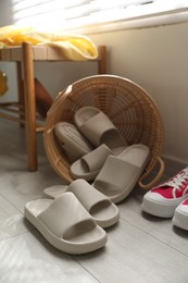 Basket with slippers for guests and sneakers in entryway at home