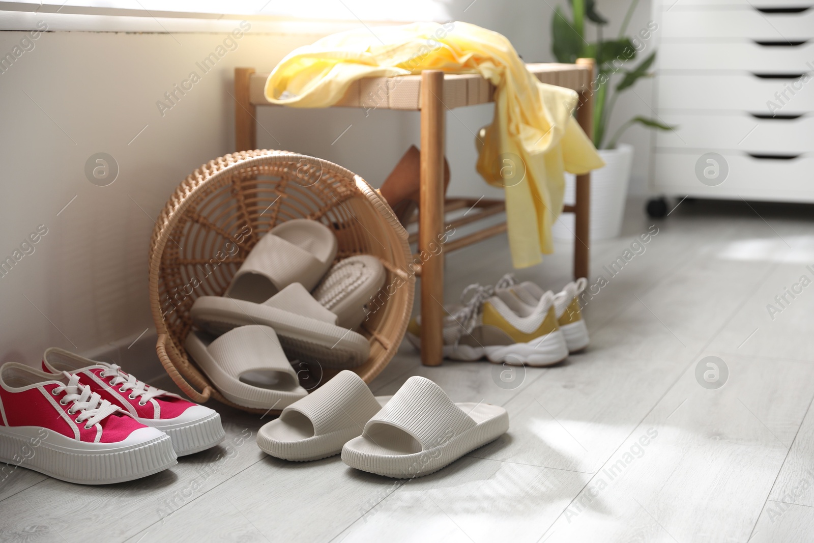 Photo of Basket with slippers for guests and sneakers in entryway at home