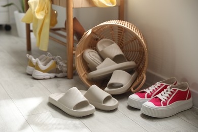 Photo of Basket with slippers for guests and sneakers in entryway at home