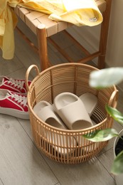 Basket with slippers for guests and sneakers in entryway at home