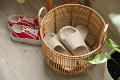 Basket with slippers for guests and sneakers in entryway at home