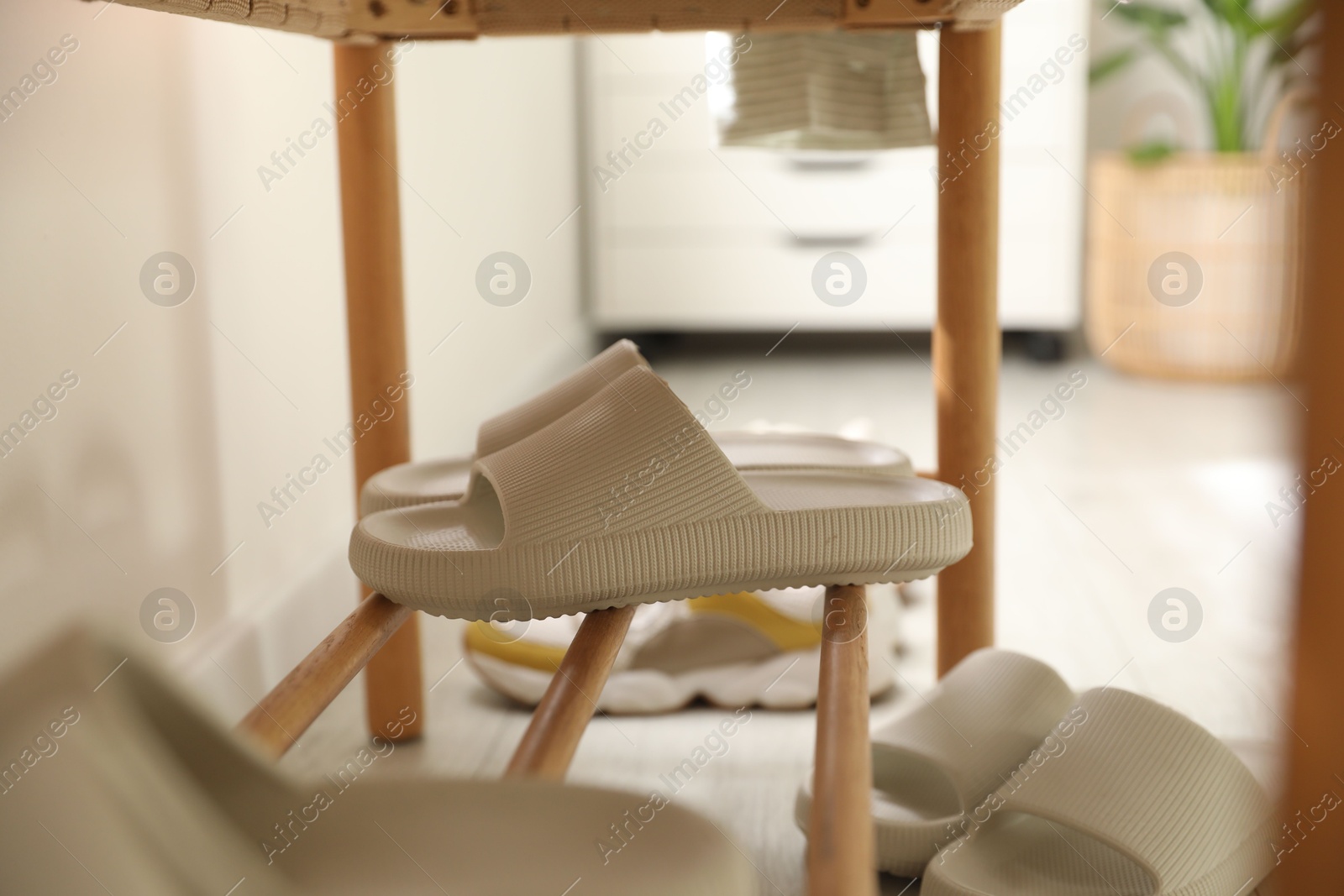 Photo of Pair of slippers on shoe rack at home