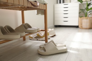 Photo of Many pairs of slippers and other shoes in entryway at home