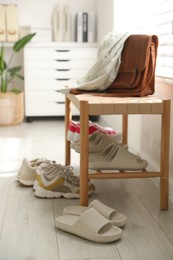 Photo of Many pairs of slippers and other shoes in entryway at home