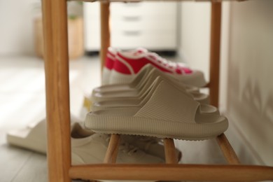 Pairs of slippers and sneakers on shoe rack at home