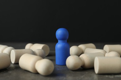 Photo of Blue piece among wooden ones on grey table, closeup