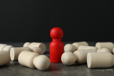 Photo of Red piece among wooden ones on grey table, closeup