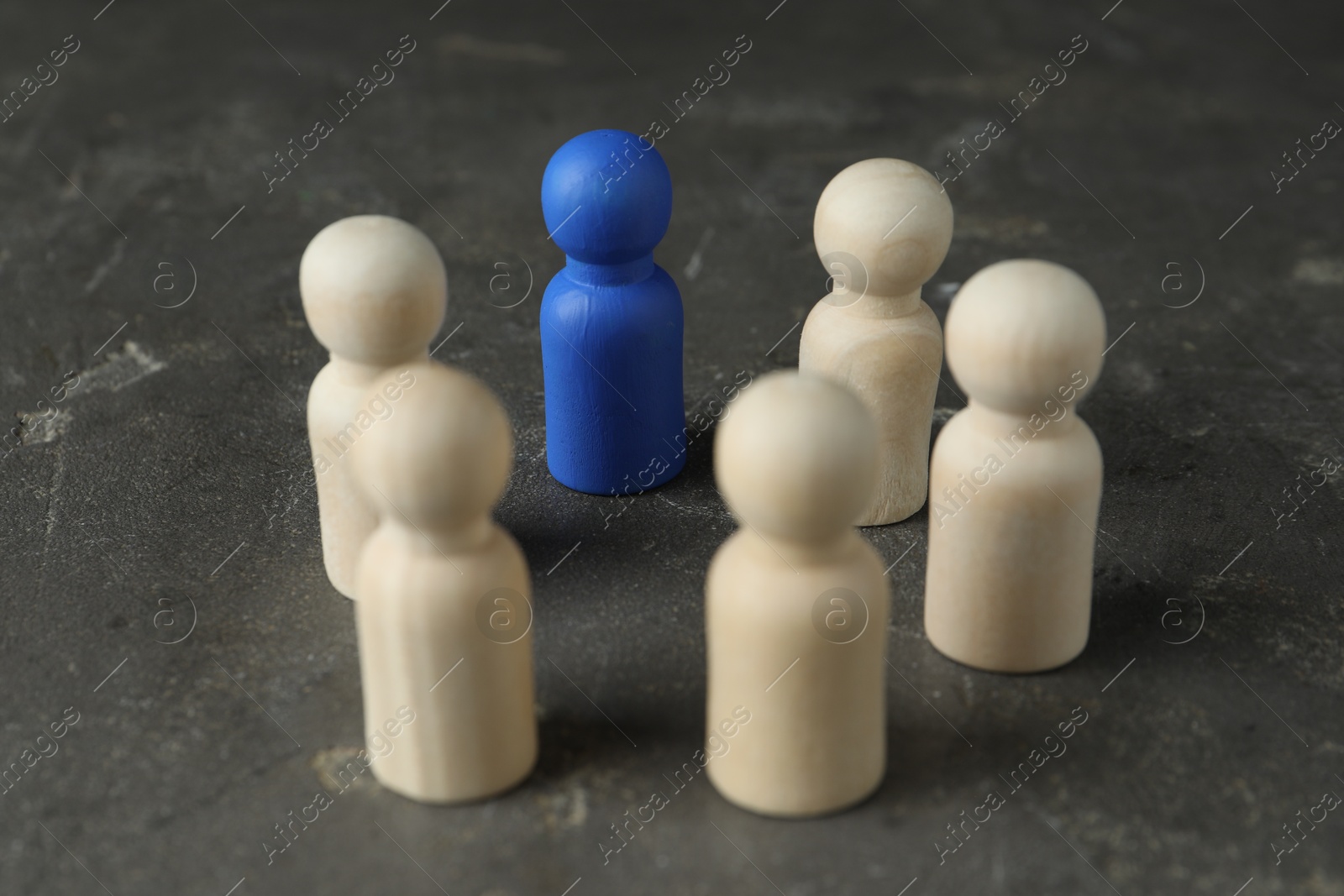 Photo of Blue piece among wooden ones on grey table, closeup